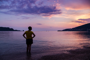 Dressed woman on pebble beach at sunset