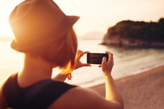 Woman Traveler With Smartphone Taking Photo Near Sea At Sunset