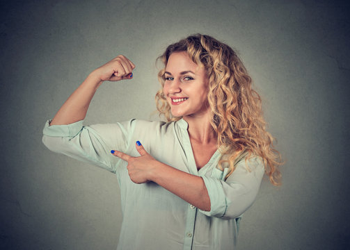 young happy woman flexing muscles showing her strength