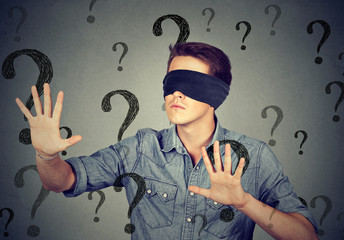 blindfolded man walking through many question marks