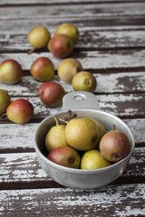 Seckel pears in a vintage pewter bowl on a rustic wooden garden table 