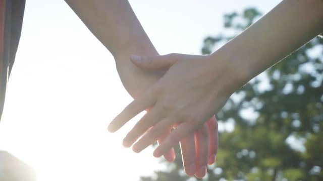 Couple holding hands at sunny day in slow motion
