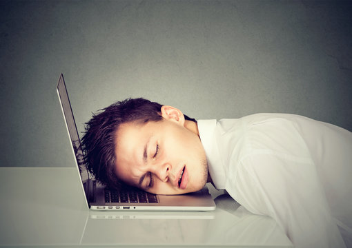 Young business man sleeping on his laptop
