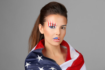 Girl with USA makeup and flag on grey background