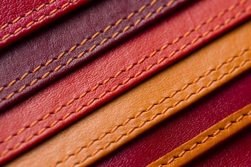 Leather samples with stitches, natural materials with seams of red, maroon, brown, orange colors...