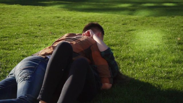 Couple in love makng summersault, tumble and handsprings on grass in slow motion