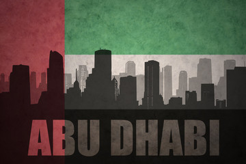 abstract silhouette of the city with text Abu Dhabi at the vintage united arab emirates flag background