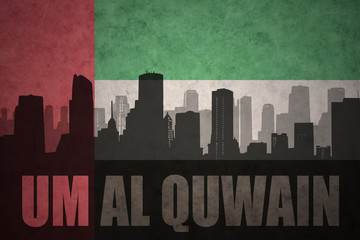 abstract silhouette of the city with text Um Al Quwain at the vintage united arab emirates flag background