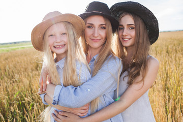 beautiful young mother and her daughters at the wheat field