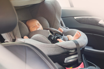 Asian cute newborn baby sleeping in modern car seat.