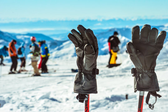 Ski gloves on the background of snowy mountains, skiers and snowboarders. Caucasus. Winter landscape. Winter sport and recreation