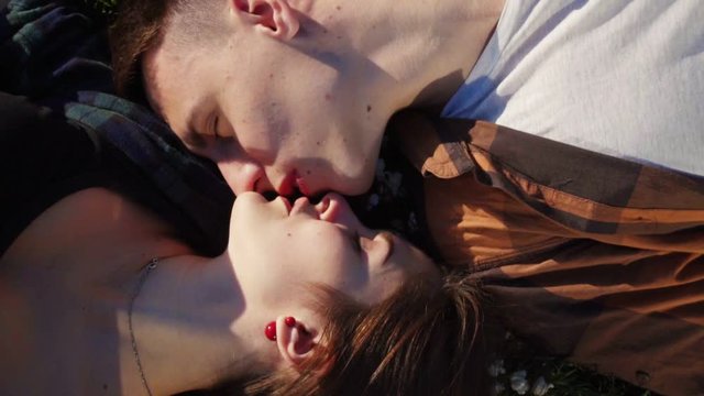 Happy love couple kiss lying on the grass