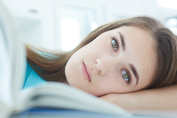 Beautiful young woman lying on  the desk near a book. Exam deadline concept. Education and self...
