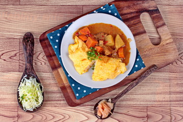 Omelet rice topped Japanese yellow curry  with sliced cabbage and pickled ginger.