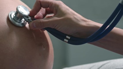 Female doctor hands listening to pregnant woman belly with stethoscope - Powered by Adobe