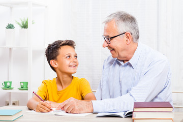 Grandfather is teaching his grandson at home.