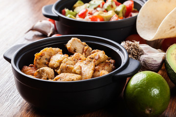 Ingredients ready for preparing chicken tacos with salsa made from avocado, tomatoes, and chilli peppers