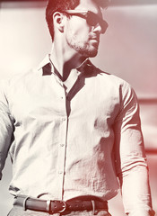 High fashion look.Young stylish confident happy handsome businessman model in suit clothes posing in the street in sunglasses