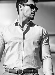 High fashion look.Young stylish confident happy handsome businessman model in suit clothes posing in the street in sunglasses
