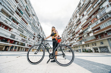 Woman standing with bike between houses.
