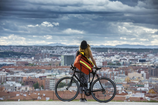 Woman with bike standing over cityscape.
