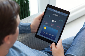 man in jeans holding tablet computer with online air ticket