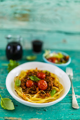 Delicious bavette pasta with bolognese sauce and fresh herbs on wooden table. Italian food.