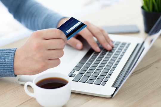 men hands with credit card on laptop keyboard and coffee