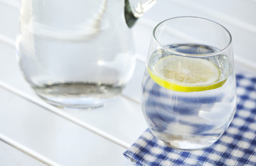 Glass of water with lemon on white background