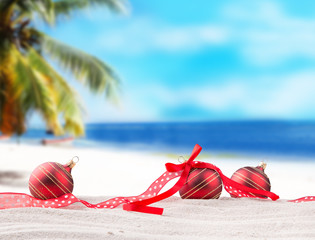 Christmas red balls, ornament on a beach - concept of a warm weather Christmas