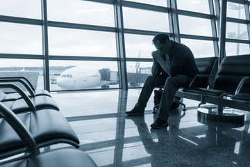 Sad man waiting for delayed flight in airport