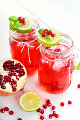 Fototapeta na wymiar Two glasses with red pomgranate juice, lemon and mint.