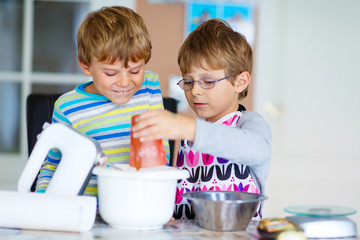 Two kid boys baking cake in domestic kitchen