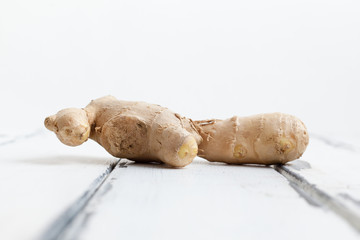 färsk ingefära på sliten vit trä bakgrund från sidan