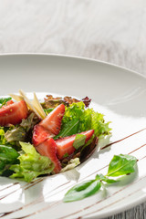 Salad greens, cheese and strawberries with balsamic sauce.