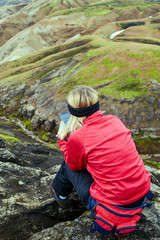 woman hiker photographer taking picture on the mountains background in Iceland