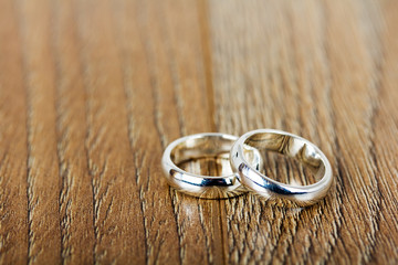 pair of wedding rings on a wooden background