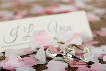 wedding rings on a wooden background with confetti