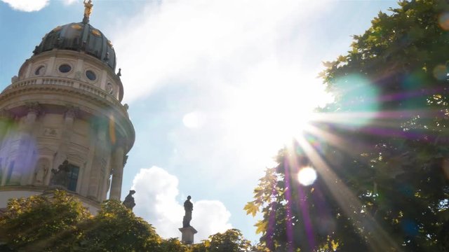 Real time pan medium shot of Franz&ouml;sischer Dom at Concert Hall square, also known as Konzerthaus at Gendarmenmarkt square in Berlin, Germany. Sun rays are over the screen.
