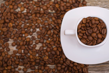 small white cup with coffee beans on wooden background