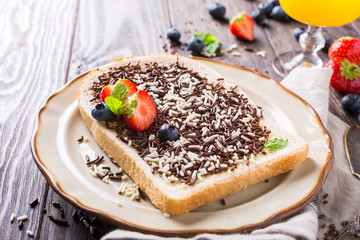 Dutch breakfast, slice of bread with hagelslag chocolate sprinkles and berries.