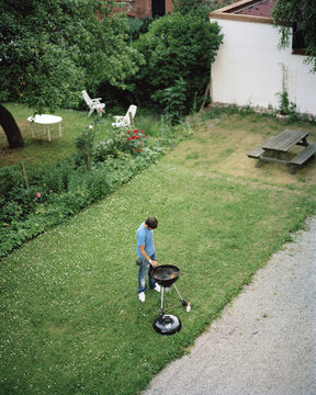 Elevated view of man cooking barbecue meal in garden