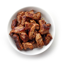 Bowl of grilled beef chunks isolated on white, from above