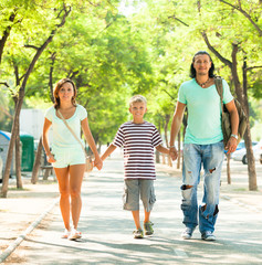 Obraz premium family of three walking in summer park