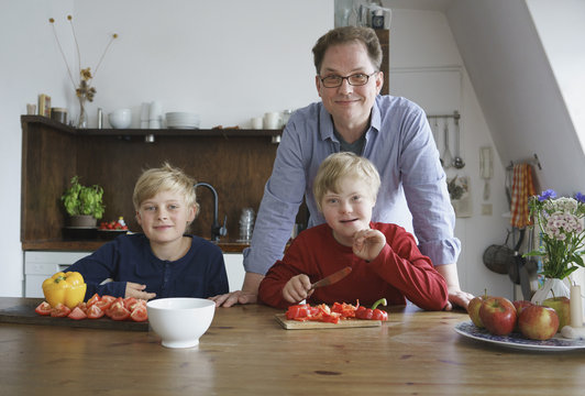 Portrait of father with sons sitting at table in kitchen