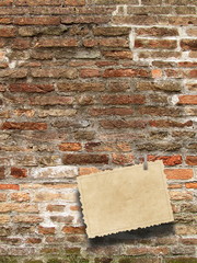 Close-up of one blank old postcard hanged by peg against old weathered brick wall background
