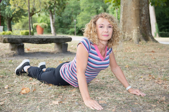 Beautiful athletic mature girl doing yoga outside- crocodile pose