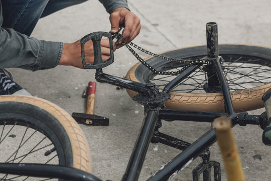 Detail view of teenager repairing bicycle chain