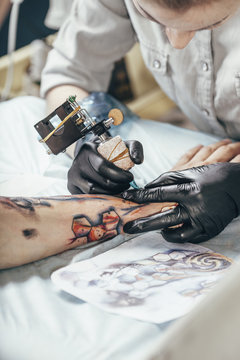 Concentrated artist tattooing design on human hand