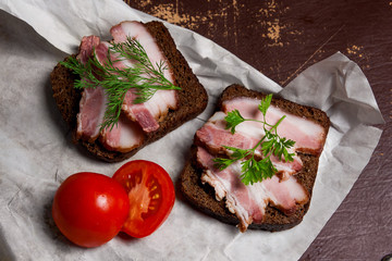 Smoked bacon with rye black bread and cuted tomatoes on the pack